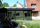 Moderne zwarte veranda met plat dak bij klassieke woning in Ronse, zijaanzicht vanuit de tuin - Van Der Bauwhede