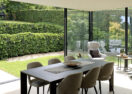 Moderne aanbouw veranda met grote eetruimte en zicht op de tuin in Hoeilaart - Van Der Bauwhede