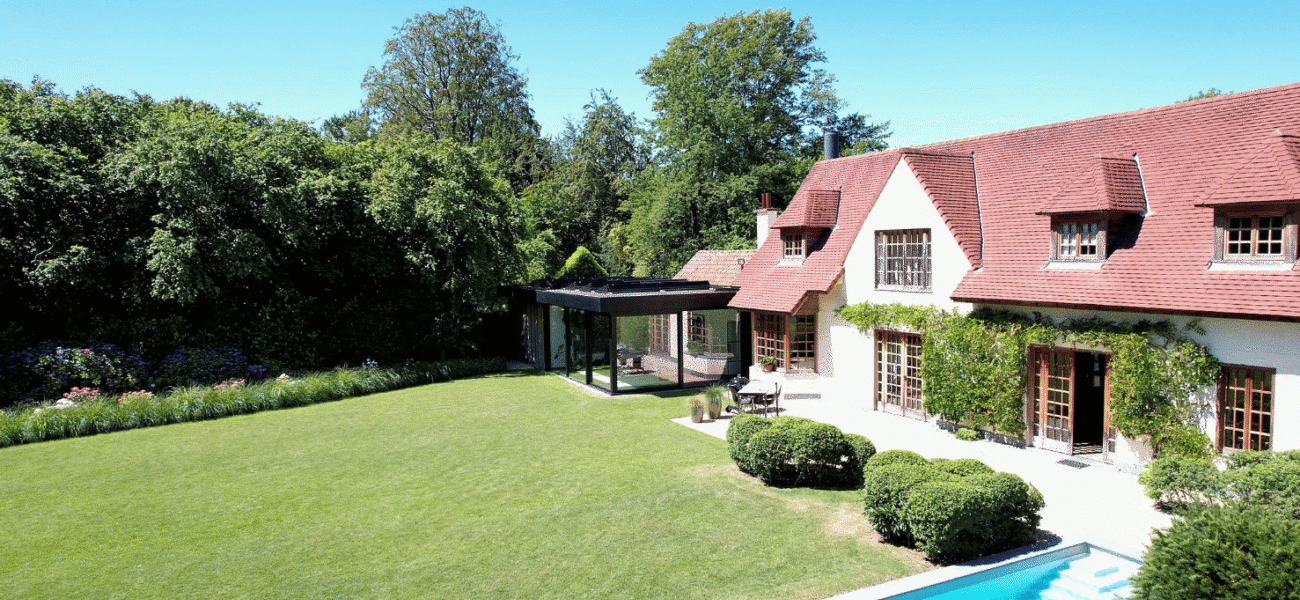 Zwarte veranda met plat dak bij klassieke woning in Ronse, zicht vanuit de tuin - Van Der Bauwhede