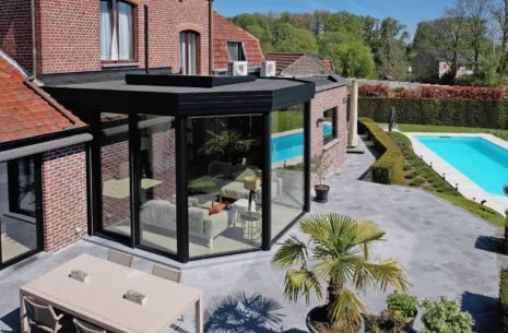 Moderne zwarte aanbouw veranda met zicht op het buitenzwembad in Ninove