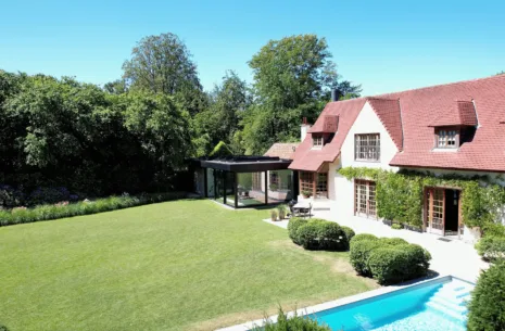 Zwarte veranda met plat dak bij klassieke woning in Ronse, zicht vanuit de tuin - Van Der Bauwhede