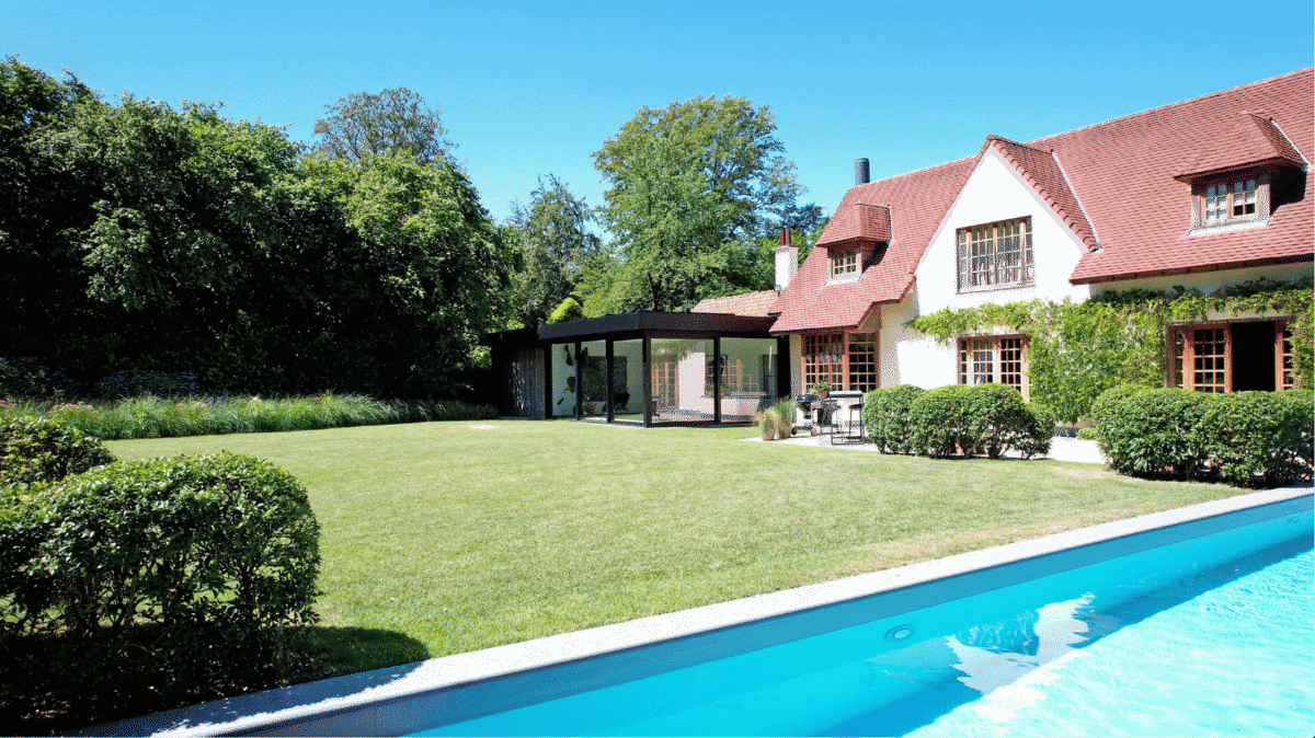 Moderne, zwarte veranda bij klassieke woning in Ronse, zicht vanuit de tuin met zwembad - Van Der Bauwhede