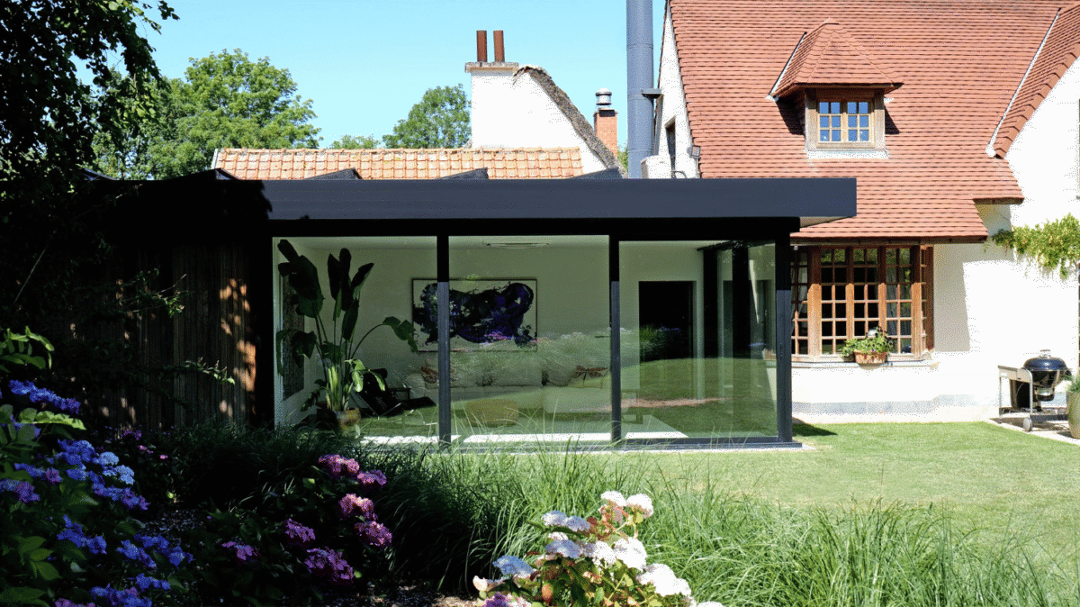 Moderne zwarte veranda met plat dak bij klassieke woning in Ronse, zijaanzicht vanuit de tuin - Van Der Bauwhede