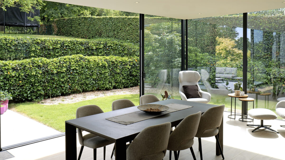 Moderne aanbouw veranda met grote eetruimte en zicht op de tuin in Hoeilaart - Van Der Bauwhede